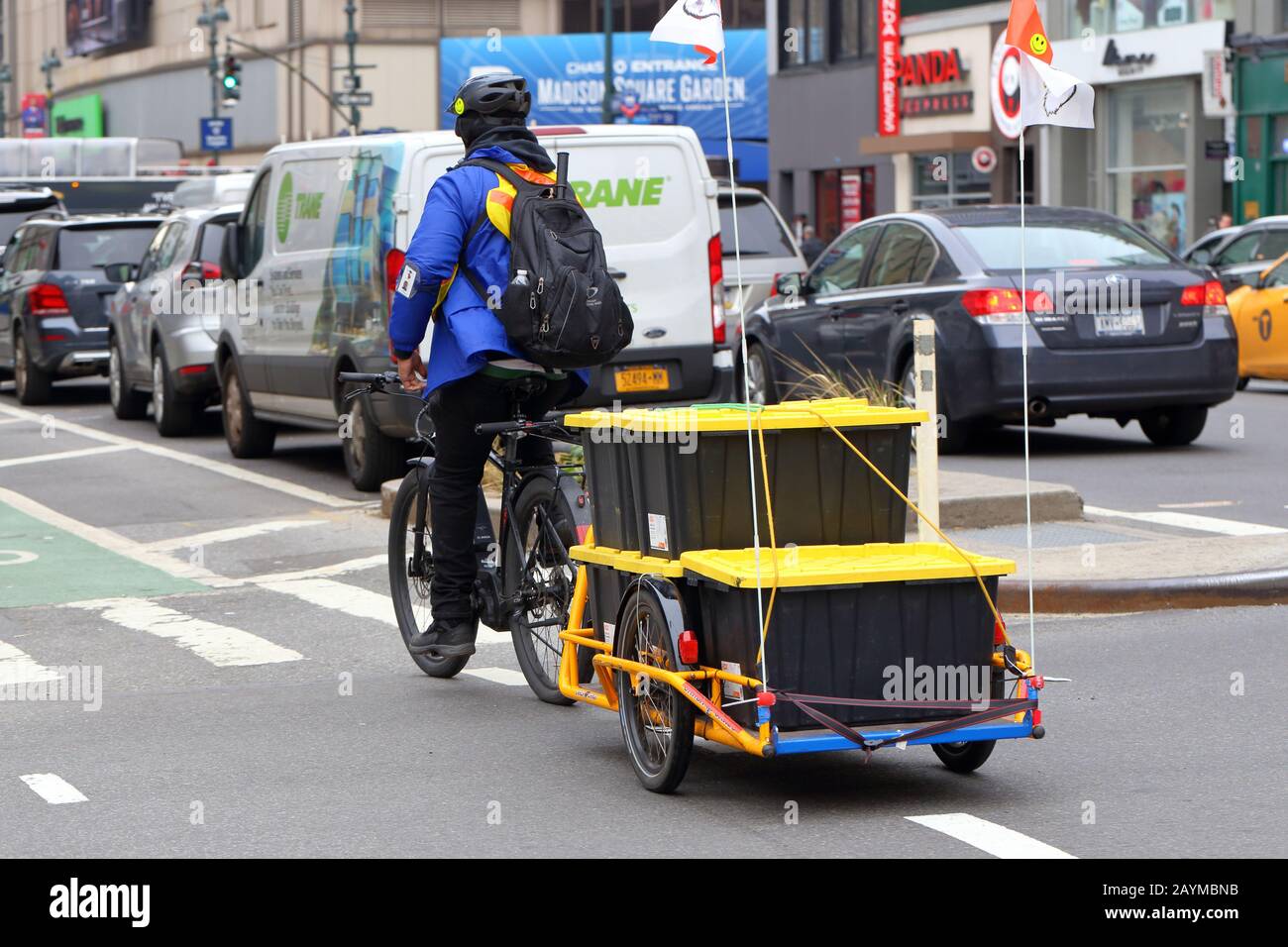 Ein Contract Bike Bote Für Den Markt Von Whole Foods mit einem E-Bike und Carla Cargo Trailer, gefüllt mit Lebensmitteln für die Hausanlieferung in New York, New York. Stockfoto