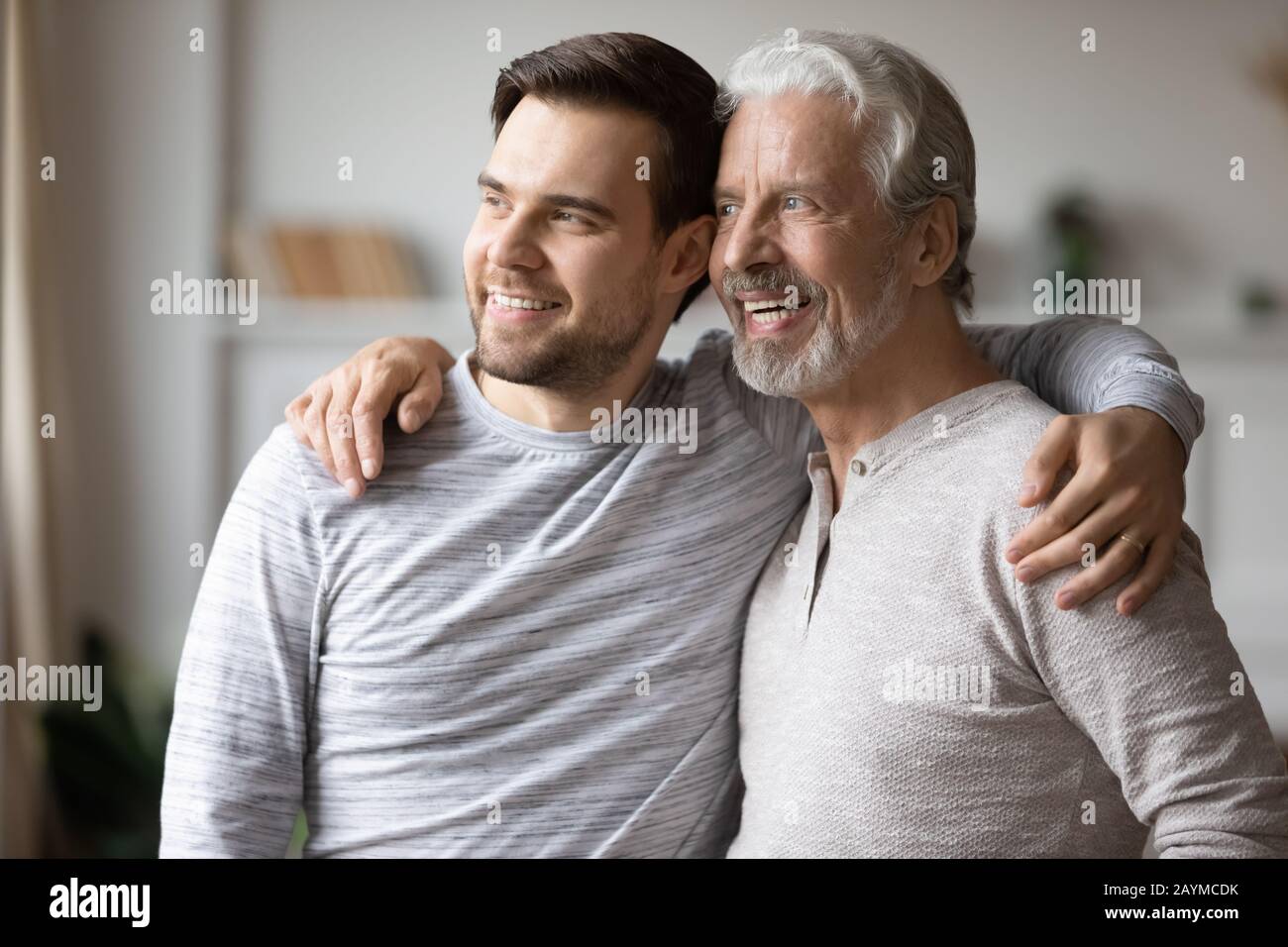 Grownup Sohn, der sich mit den Schultern eines glücklichen Vaters mittleren Alters umarmte. Stockfoto