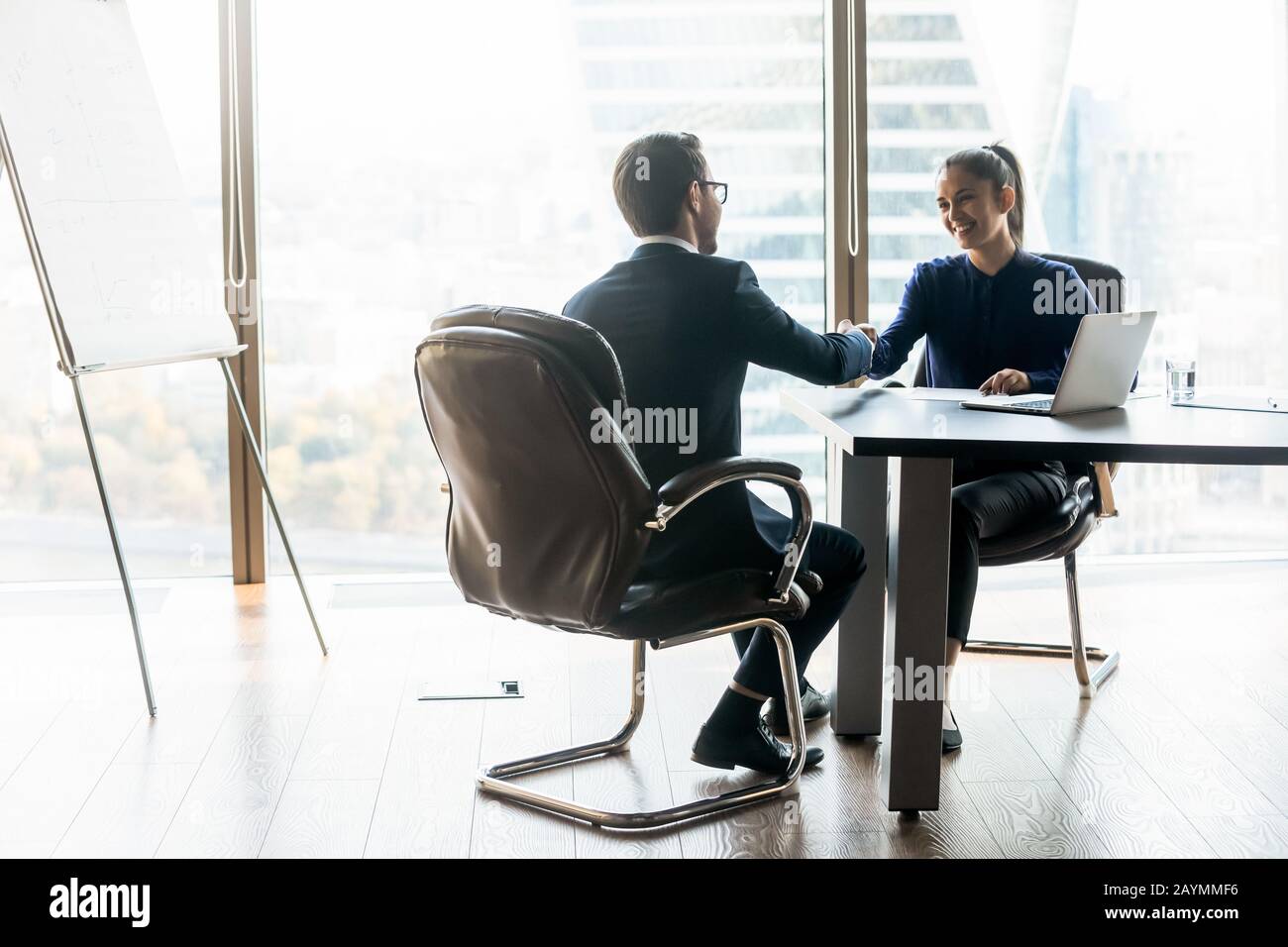 Glückliche Geschäftsfrau schüttelt die Hände mit dem Arbeitssuchenden des Geschäftsmannes in der Klage. Stockfoto