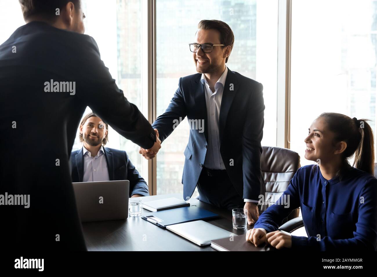 Glücklicher erfolgreicher Geschäftsmann im Anzug, der die Hand des Bewerbers schüttelt. Stockfoto