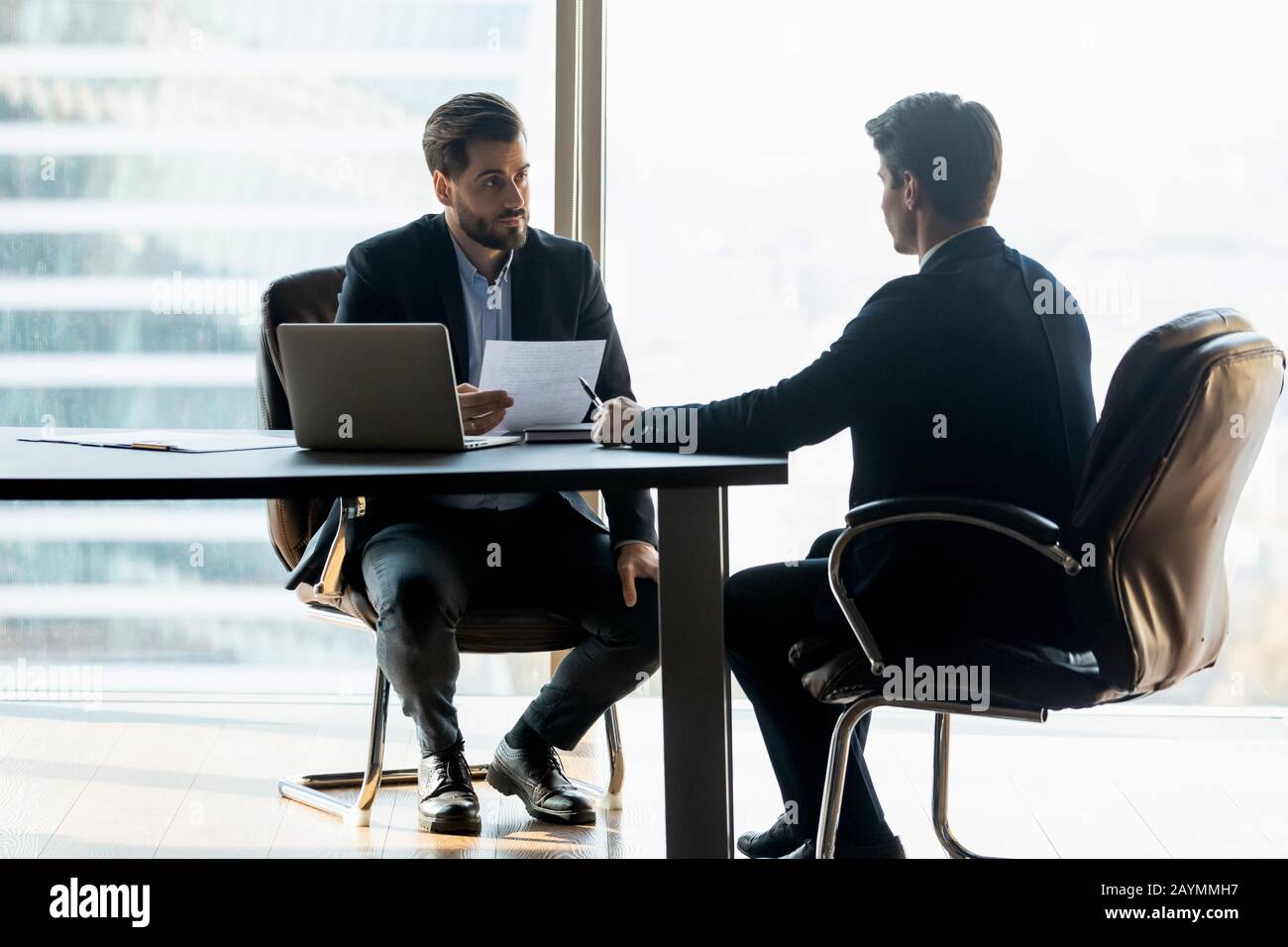 Seriöse Unternehmer im Anzug, die den lebenslauf halten, um neuen Kandidaten anzuhören. Stockfoto