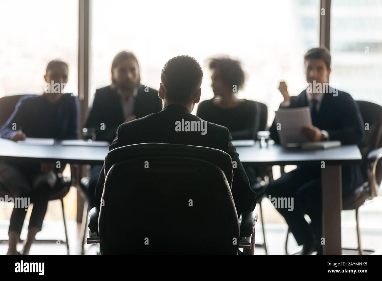 Gutaussehender Mann, der zurück vor HR sitzt, verschiedene Geschäftsleute. Stockfoto