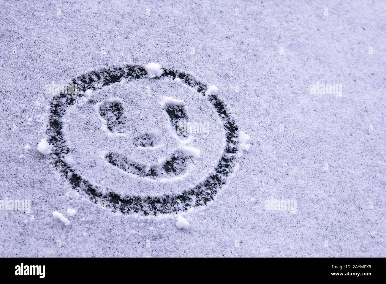 Lächelndes Emoticon auf dem ersten Schnee auf der Windschutzscheibe Stockfoto