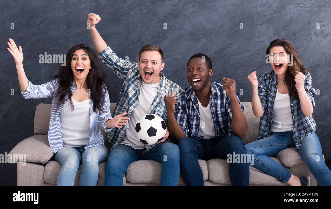 Aufgeregt multiethnische Freunde, die zu Hause Fußball sehen Stockfoto