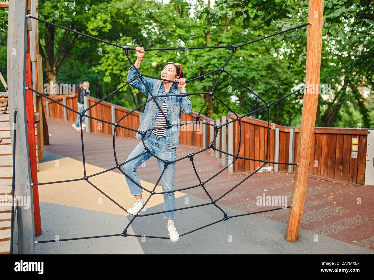 Eine infantile und glückliche Frau, die auf einer Kinderrutsche auf einem Spielplatz sitzt Stockfoto