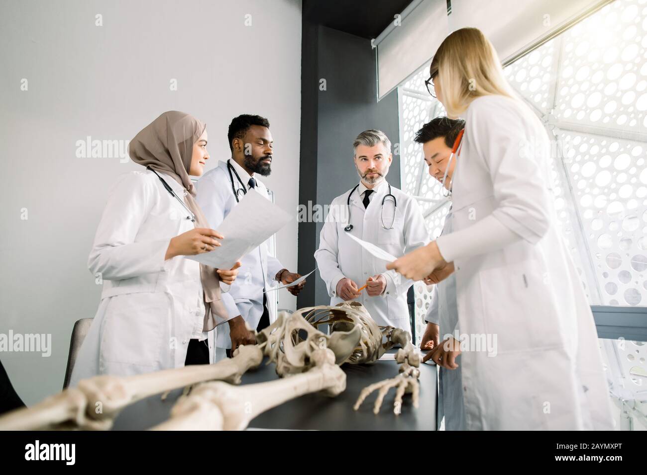 Team von jungen verschiedenen Ärzten, Studenten, Wissenschaftlern in weißen Labcoats, die über das Treffen im modernen Klassenzimmer diskutieren. Junge Ärzte Kollegen Stockfoto