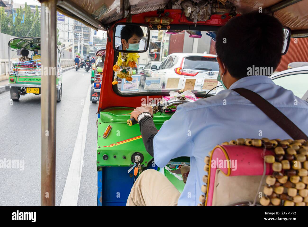 Ein Tuk-Tuk-Fahrer trägt eine Gesichtsmaske, um ihn vor Coronavirus COVID-19 zu schützen, während er durch die Straßen von Bangkok, Thailand fährt. Stockfoto