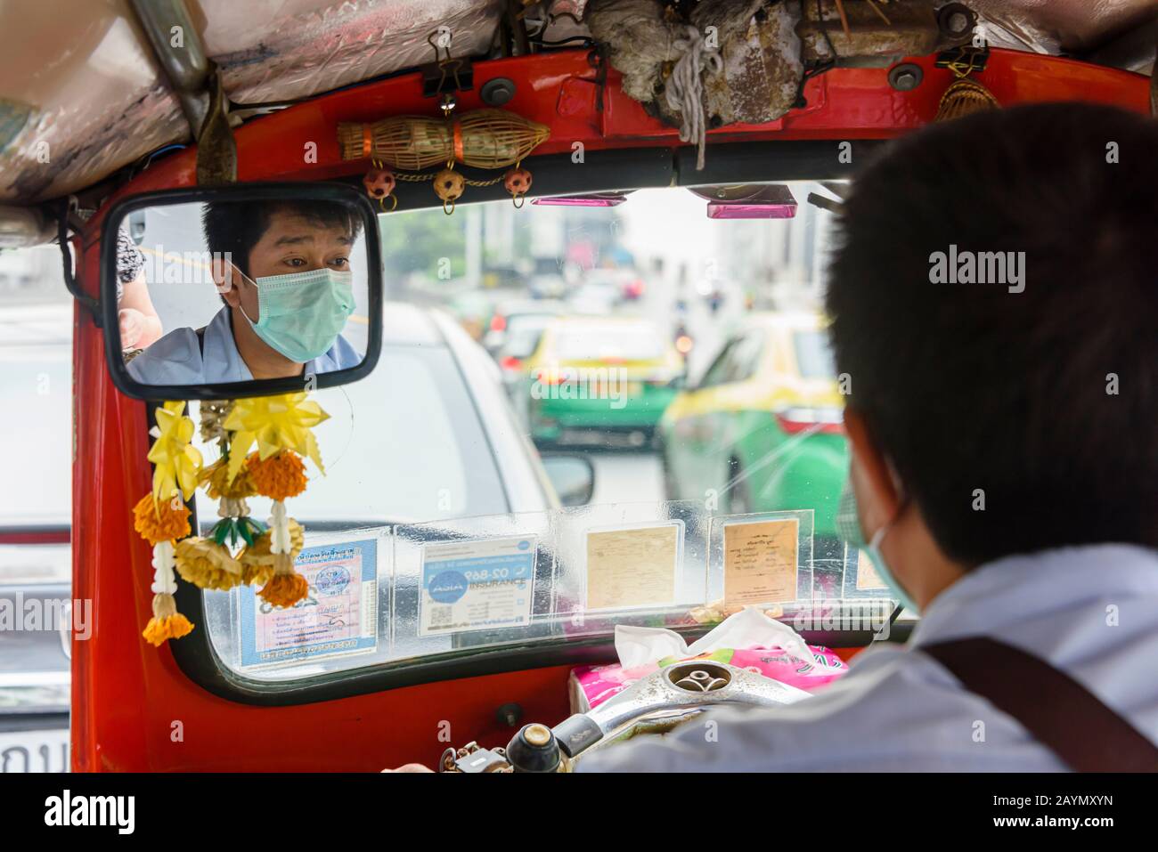 Ein Tuk-Tuk-Fahrer trägt eine Gesichtsmaske, um ihn vor Coronavirus COVID-19 SARS-COV-2 zu schützen, während er durch die Straßen von Bangkok, Thailand fährt. Stockfoto