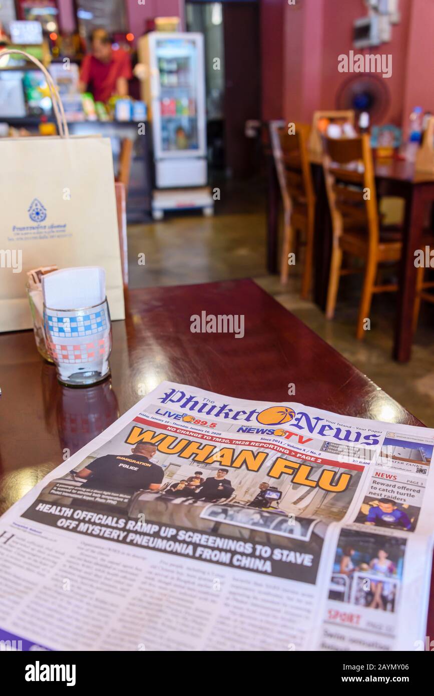 Die Phuket News mit der Überschrift "Wuhan Grippe" auf einem Tisch in einem Café in der Altstadt von Phuket, Thailand. SARS-COV-2 Stockfoto