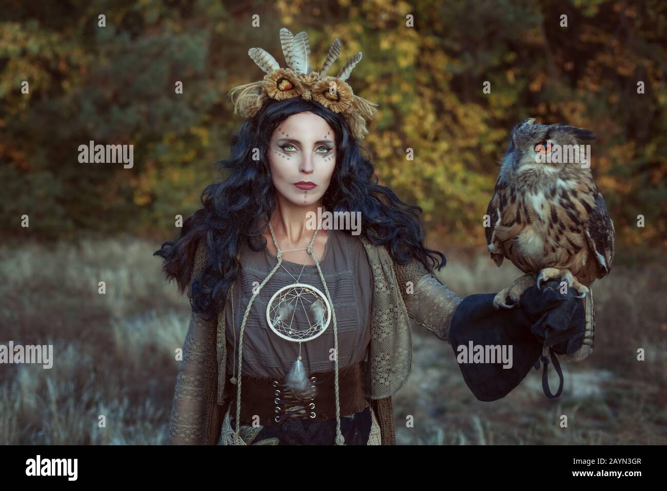 Porträt einer Schamanin im Wald. Sie hat eine Adler-Eule in der Hand. Stockfoto