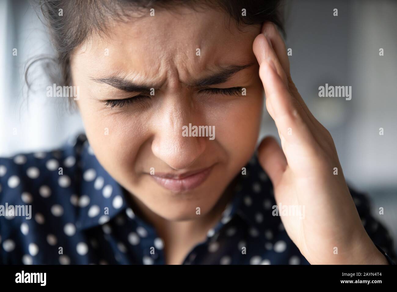 Erschöpfte ethnische Mädchen leiden zu Hause unter Kopfschmerzen Stockfoto