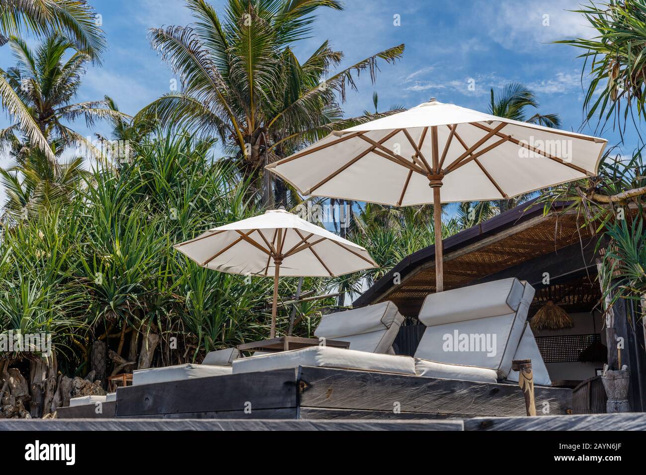 Sonnenliegen und Sonnenschirme aus weißem Stoff am Strand. Bali, Indonesien. Stockfoto