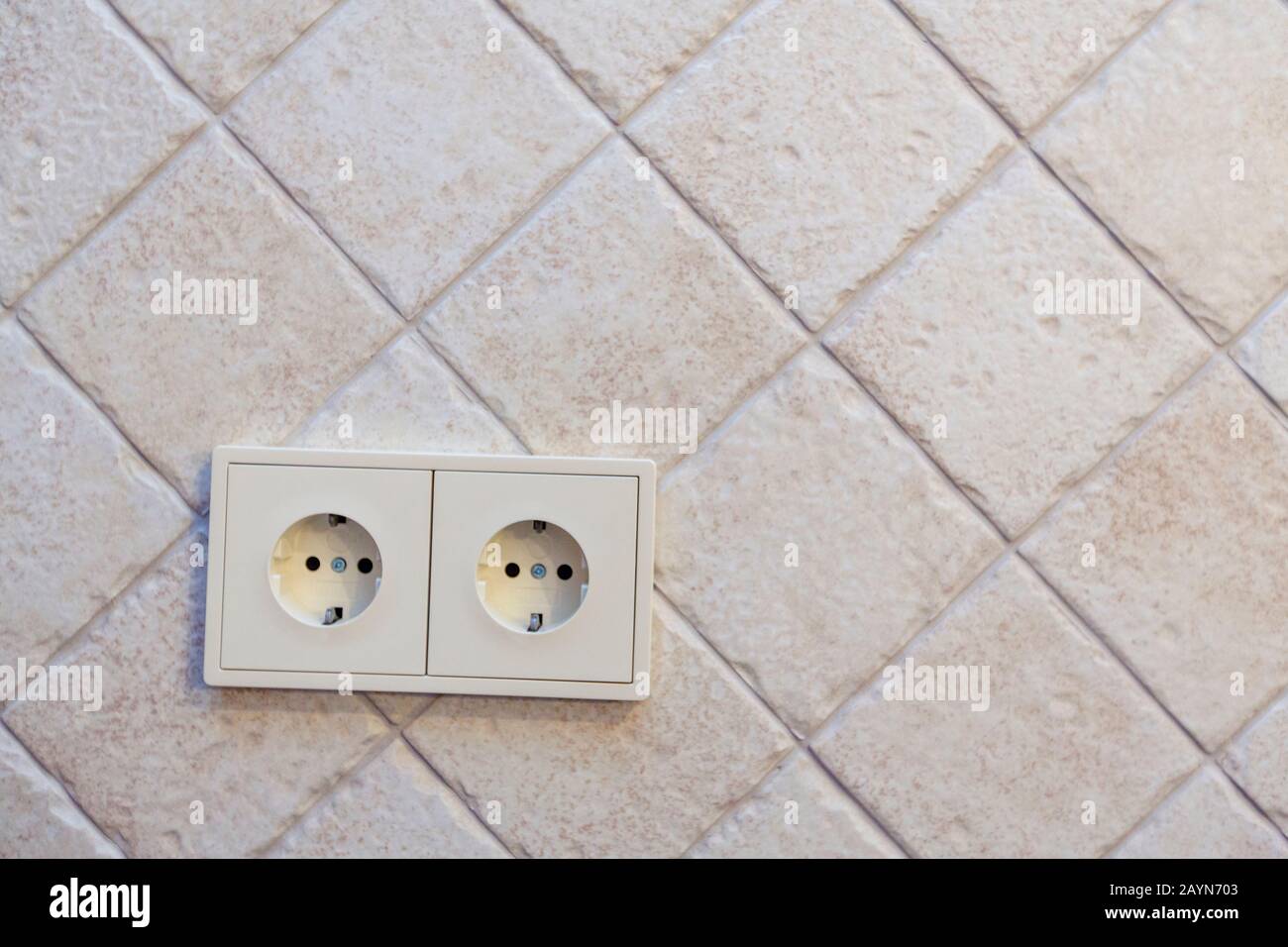 Schöne beige Fliesen mit unebenen Kanten sind diagonal ausgelegt. Hintergrund. Doppelauslass unten links. Stockfoto