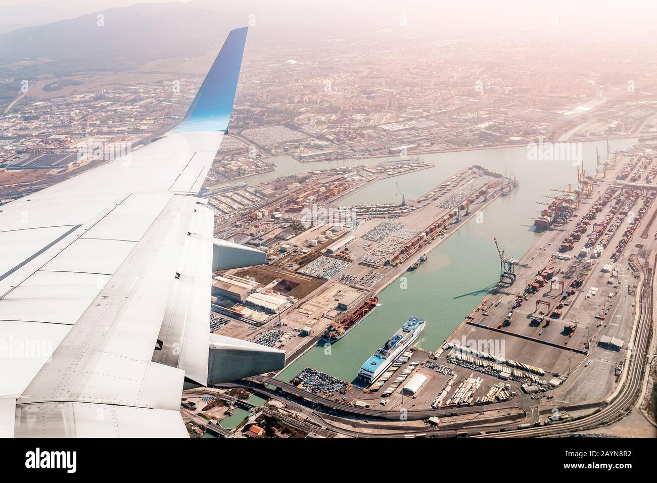 Flugzeugflügel mit Blick auf den Industrietransporthafen Stockfoto