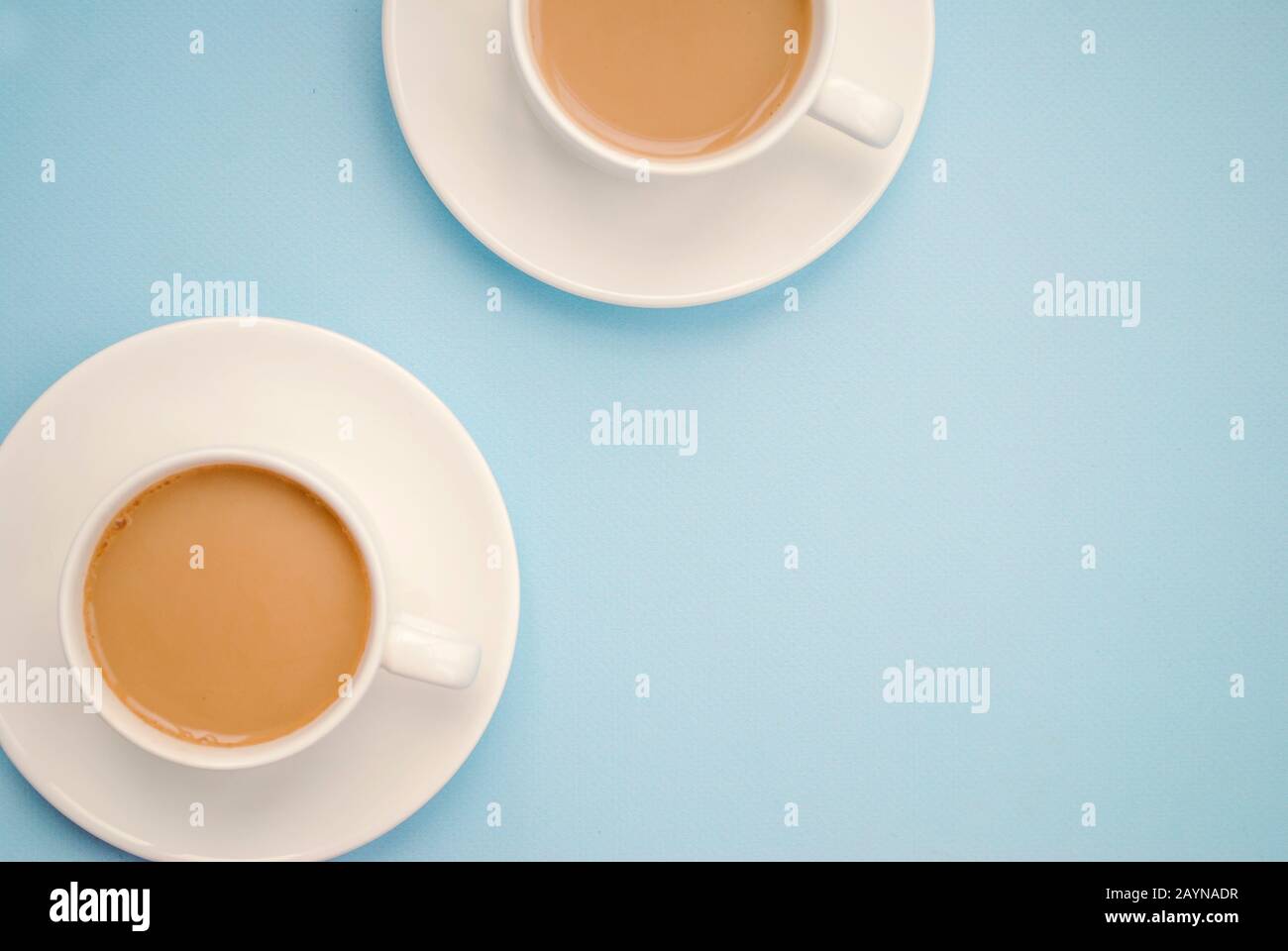 Zwei weiße Tassen Kaffee mit Milch, hellblauer Hintergrund, Draufsicht. Americano. Kopierbereich Stockfoto