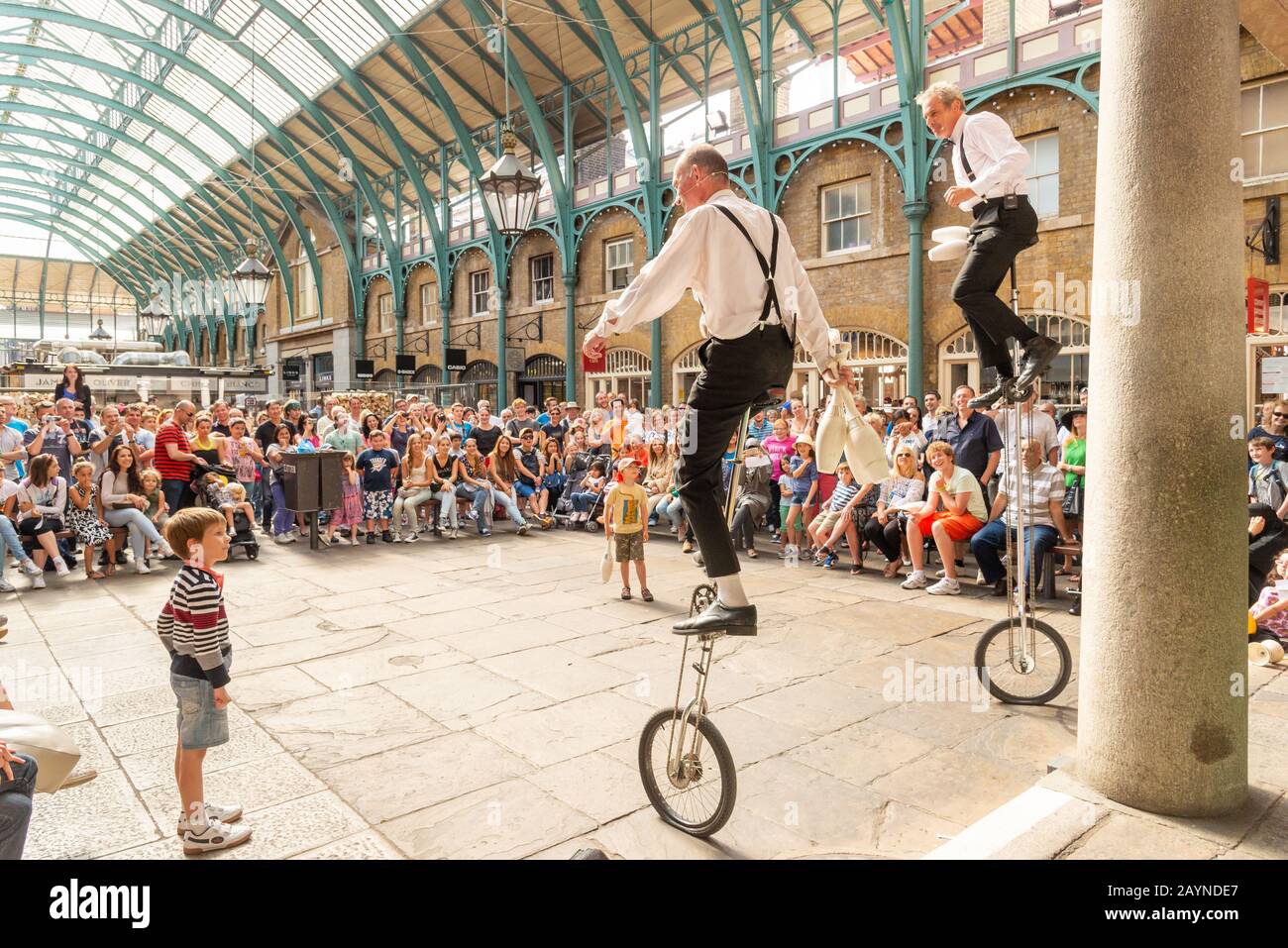 Kinder beobachten Einrad Durchführung Busker in Covent Garden, London, Großbritannien Stockfoto