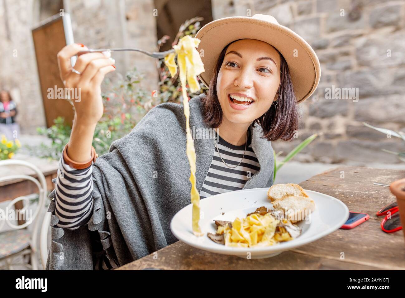 Glückliche asianerin, die Pasta mit Trüffel im italienischen Restaurant im Freien isst Stockfoto