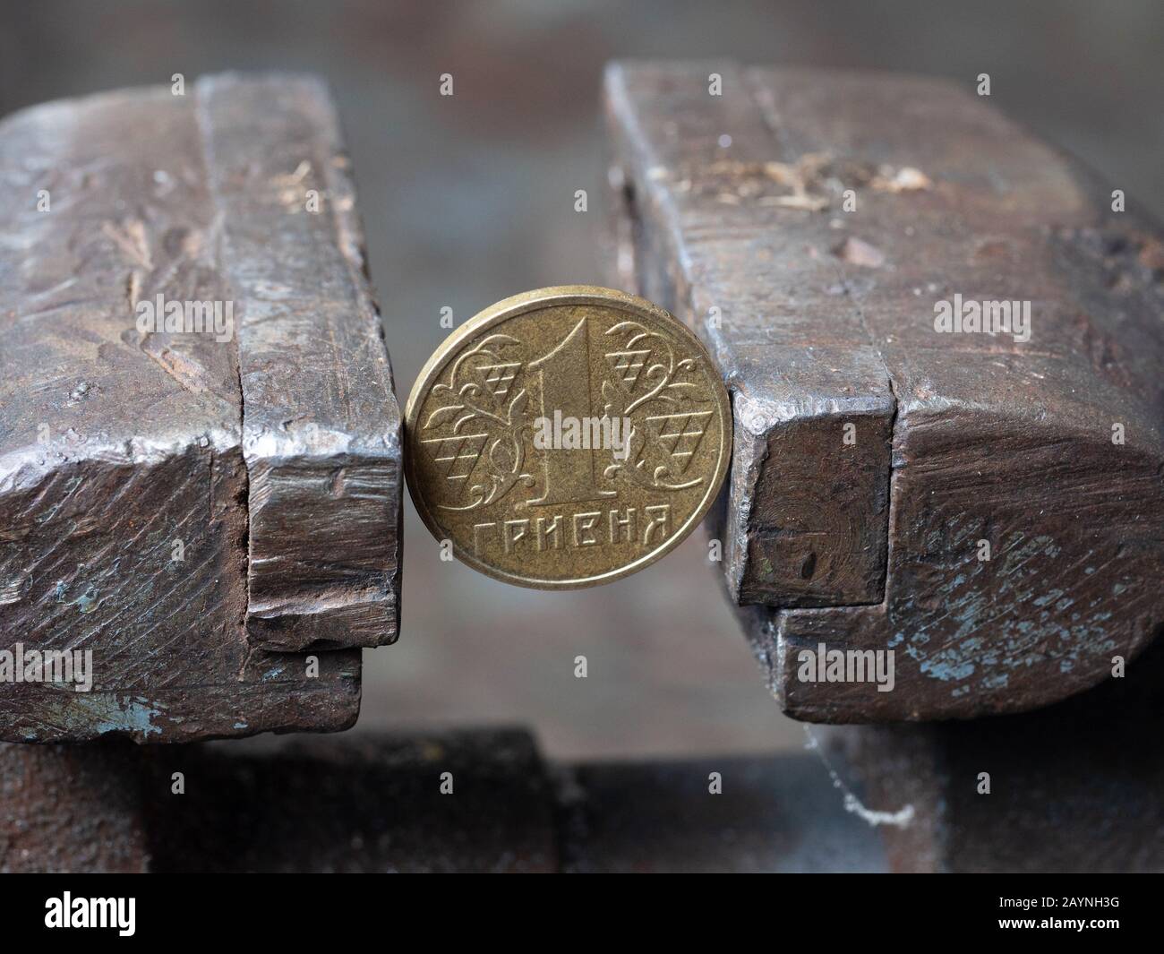 Hryvnya Münze in einen Metall-Schraubstock eingeklemmt. Währung und ukrainische Wirtschaft unter dem Ansturm, das Konzept der finanziellen Probleme und der Krise Stockfoto