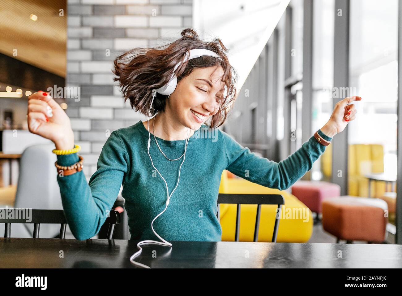Junge glückliche Frau mit Kopfhörern, die ihr Lieblingslied über Wi-Fi Internet hört Stockfoto