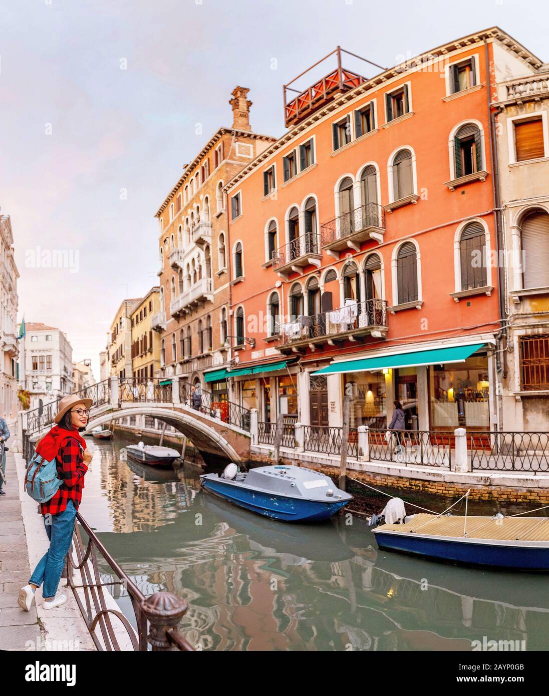 Junge, glückliche asiatische Reisende Frau am Pier eines schmalen Kanals und einer schmalen Straße in Venedig. Urlaub in Italien Konzept Stockfoto