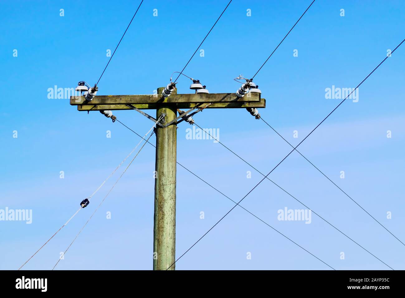Ein Holzpfosten mit Kabeln gegen einen blauen Himmel. Stockfoto