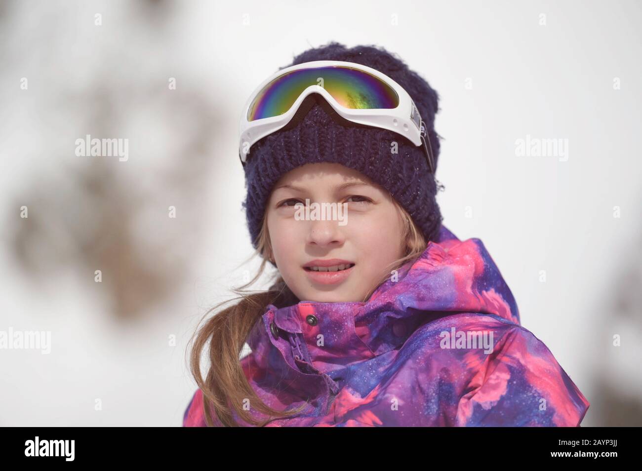 Schöne aktive lächelnde fröhliche kleine kaukasische junge Frau in Wollmütze und Snowboardjacke mit Ski-Googles im Winter Outdoor-Freizeit-Nachbildung Stockfoto