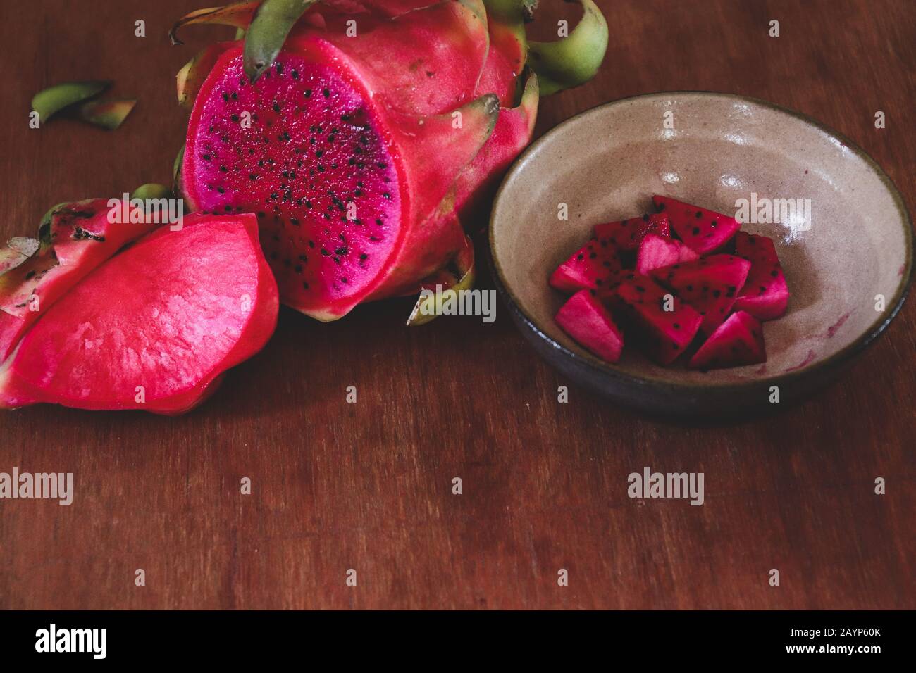 Rote Drachenfrucht in Scheiben vor Holzhintergrund, die das Konzept des Sommers, gesunde Ernährung, Veganismus und gesunden Lebensstils zeigt Stockfoto