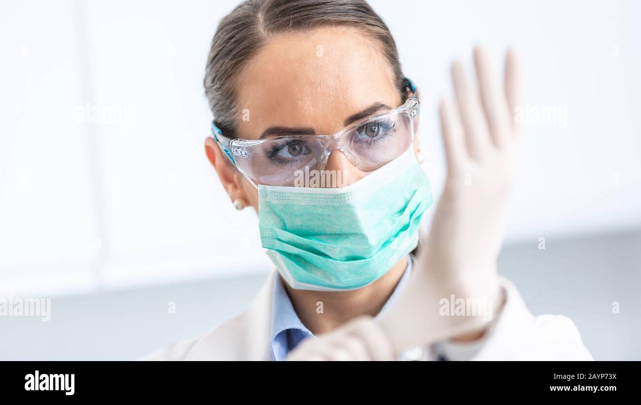 Arzt Frau Chirurg Spezialist für sterile Kleidung setzen auf OP-Handschuhe. Stockfoto