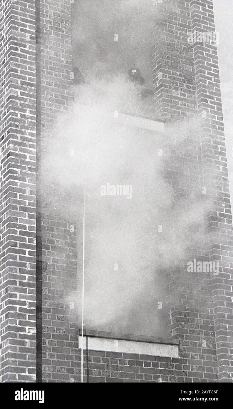 1960er Jahre, historisch, Feuerwehrtraining, Feuerwehrmann an der Spitze eines rauchenden Bohrturms, mit Hebezeug, Fleetwood, England, Großbritannien. Stockfoto