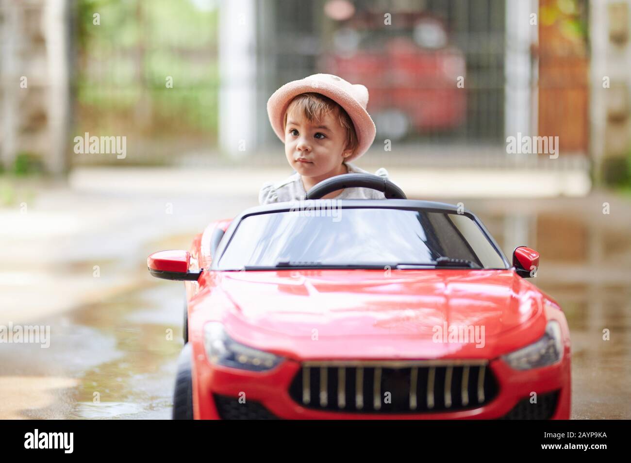 Baby Girl Lernfahrt auf rotem Spielzeugauto draußen im Park Stockfoto