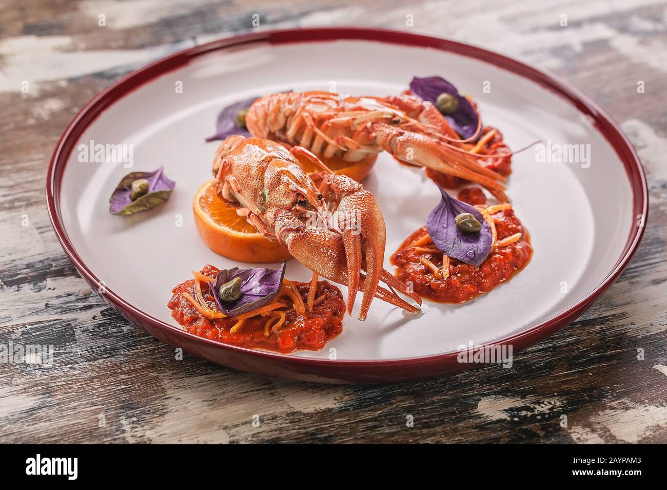 Gekochte Flusskrebse. Delikatesse mit Chili Pfeffersauce, Basilikum und Kapern auf einem Teller. Gourmetküche Stockfoto