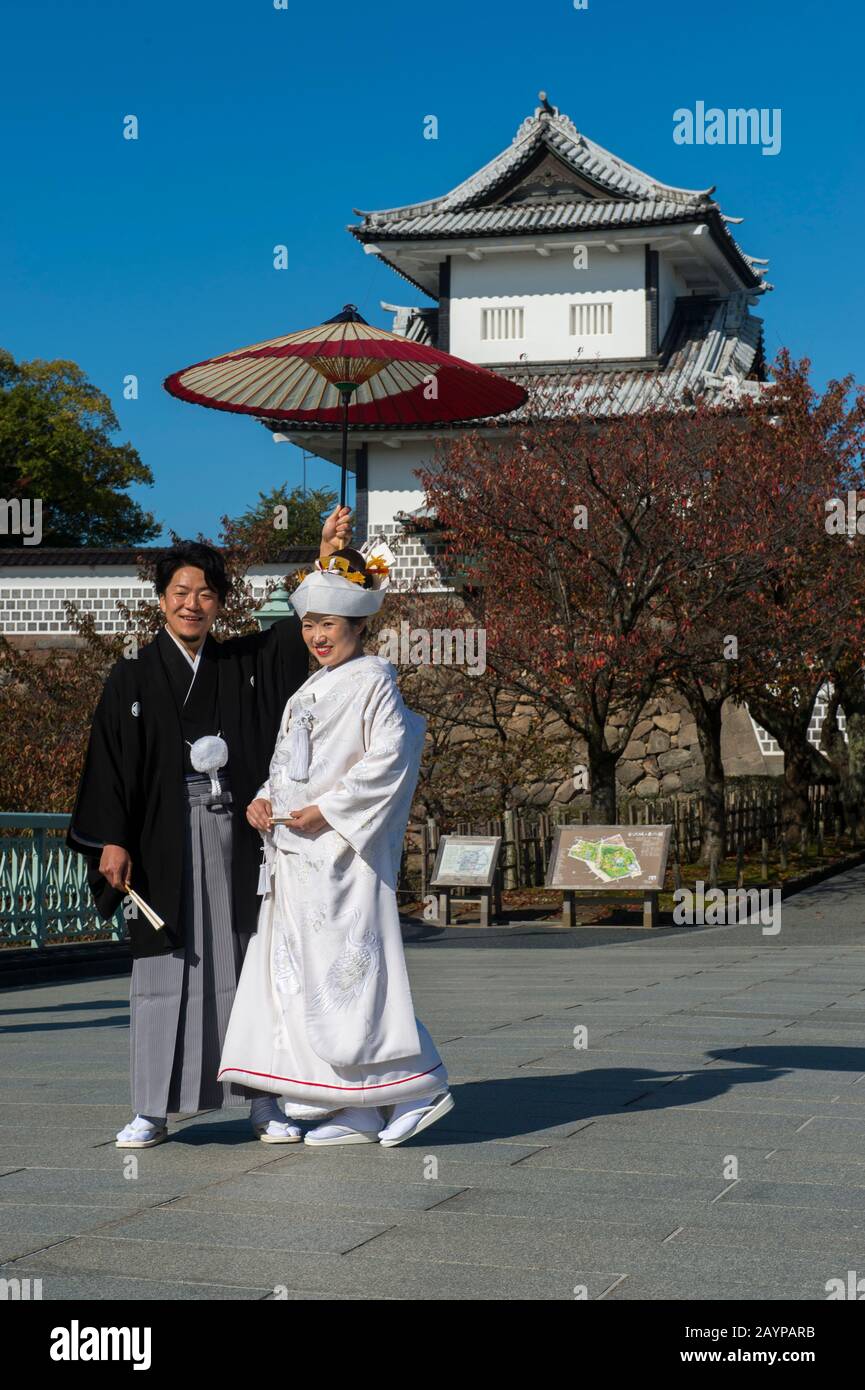 Ein Hochzeitspaar in traditioneller Kleidung posiert vor dem Schloss im Kaanazawa-Schlosspark in Canazawa, Präfektur Ishikawa, auf Honshu Isla Stockfoto