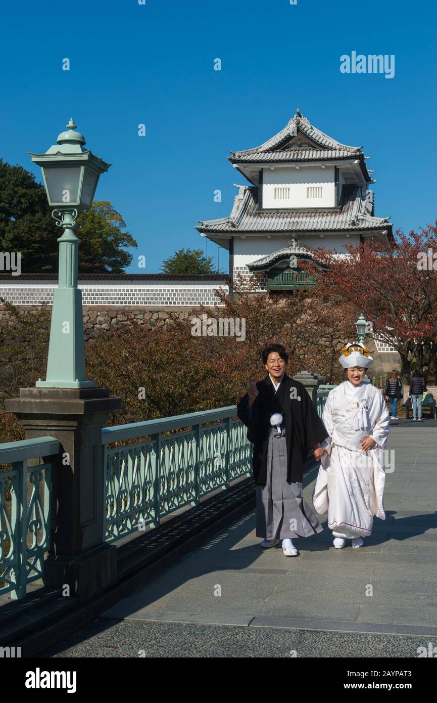 Ein Hochzeitspaar in traditioneller Kleidung posiert vor dem Schloss im Kaanazawa-Schlosspark in Canazawa, Präfektur Ishikawa, auf Honshu Isla Stockfoto