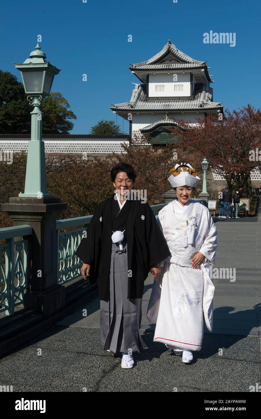 Ein Hochzeitspaar in traditioneller Kleidung posiert vor dem Schloss im Kaanazawa-Schlosspark in Canazawa, Präfektur Ishikawa, auf Honshu Isla Stockfoto