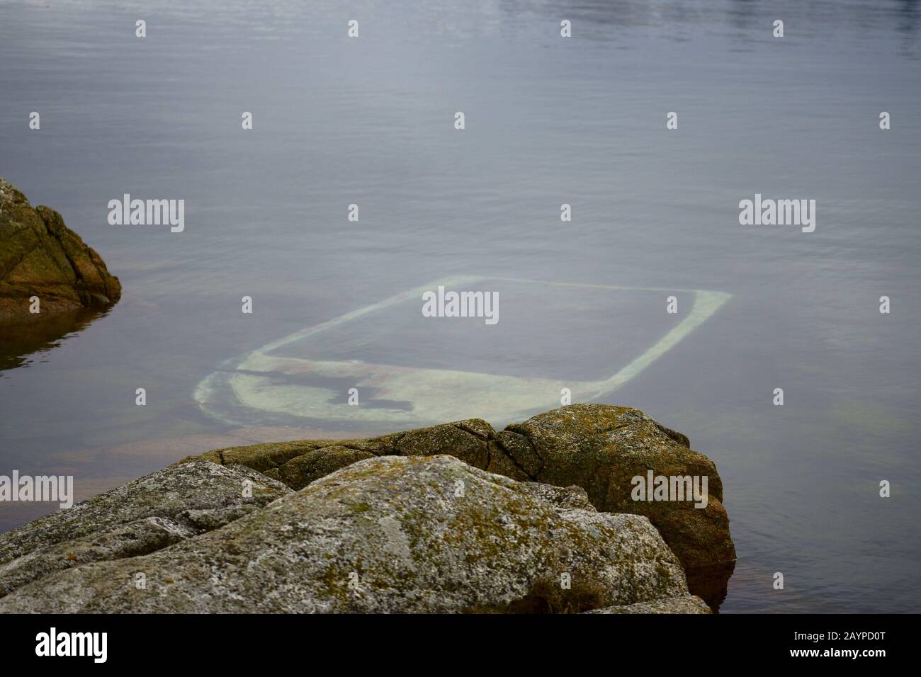 Versunkenes Boot unter den Felsen. Stockfoto