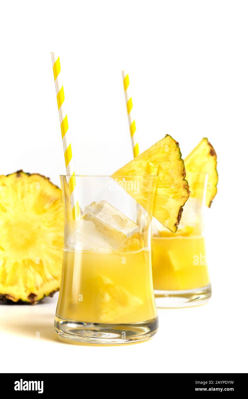 Glas Ananasaft mit einem auf weißem Hintergrund isolierten Strohhalm und Ananasscheiben Stockfoto