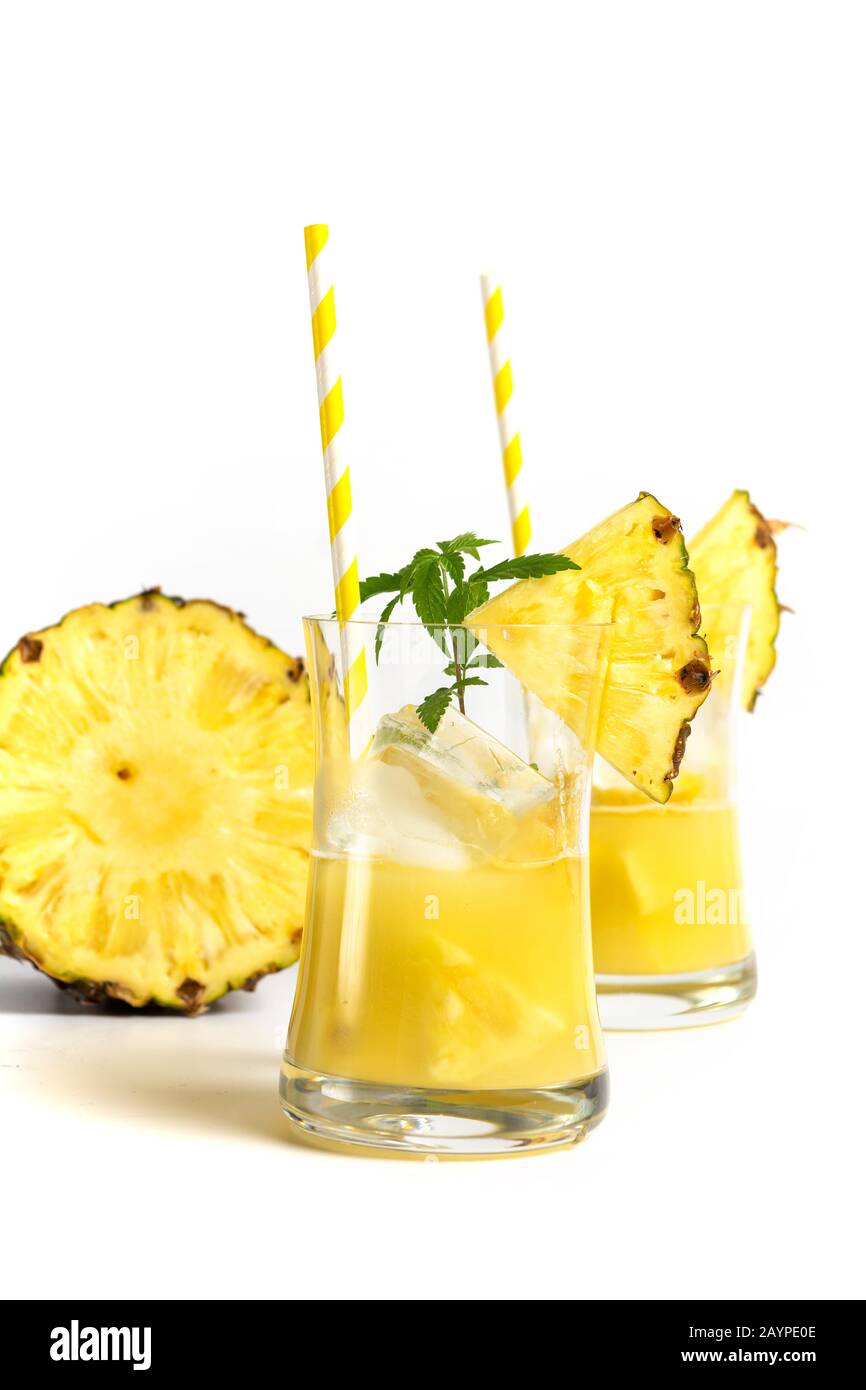 Glas Ananasaft mit einem auf weißem Hintergrund isolierten Strohhalm und Ananasscheiben Stockfoto