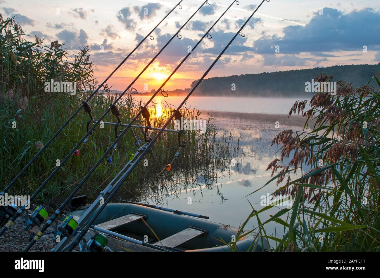 Fischer mit Angelruten bei Sonnenaufgang auf dem See Stockfoto