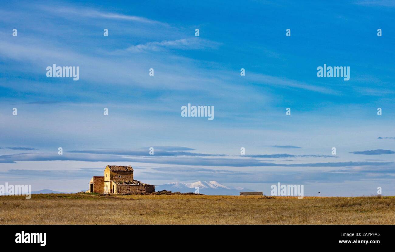 Naturlandschaft mit blauem Himmel und schneebedecktem Berghintergrund mit ländlichem Haus in der Herbstsaison und Agrarfeld auf einer Wiese Stockfoto