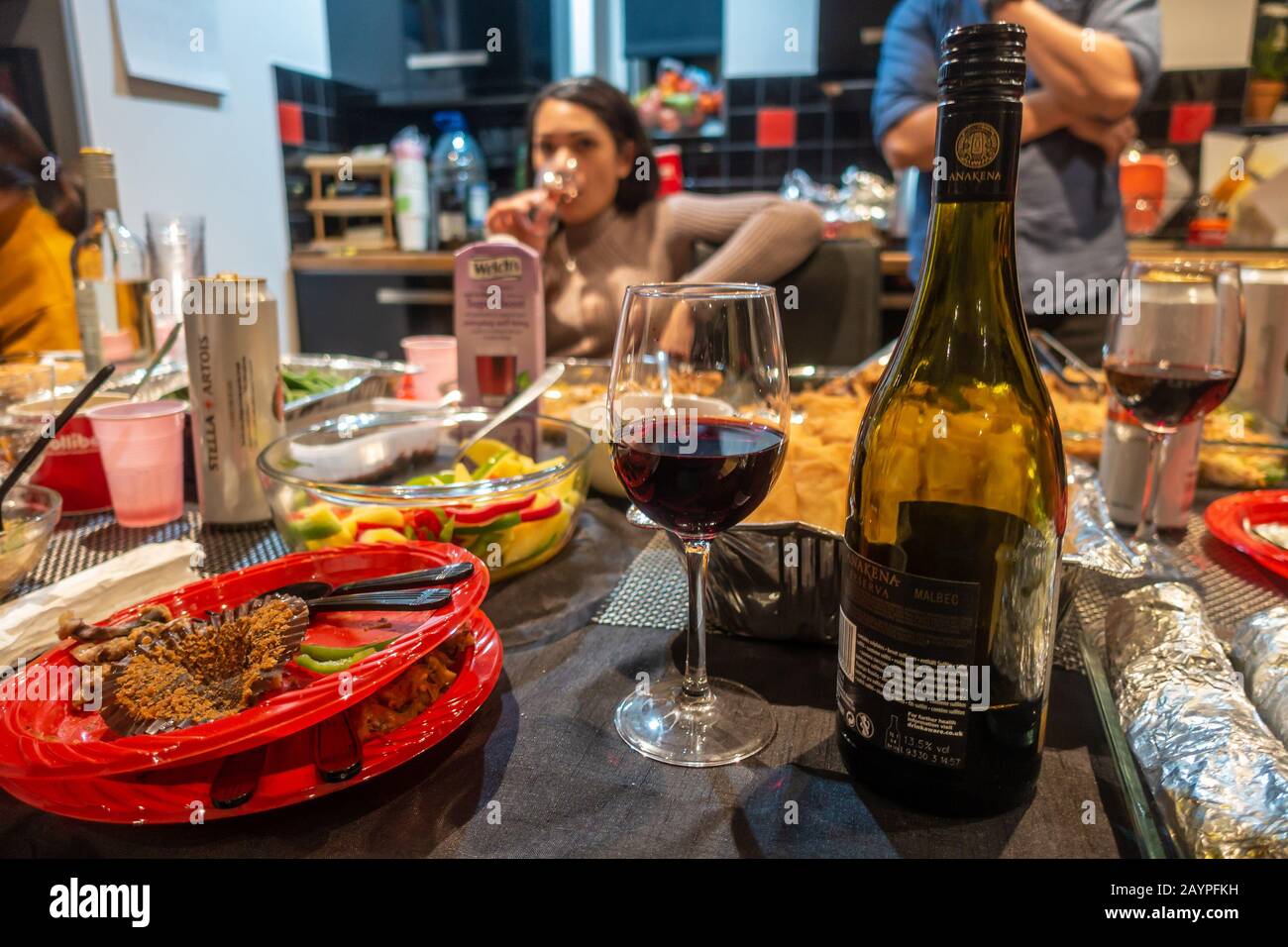 Essen, trinken, Gläser, Flasche Wein, Plastikplatten auf einem Tisch bei einer Buffetmahlzeit auf einer Party. Stockfoto