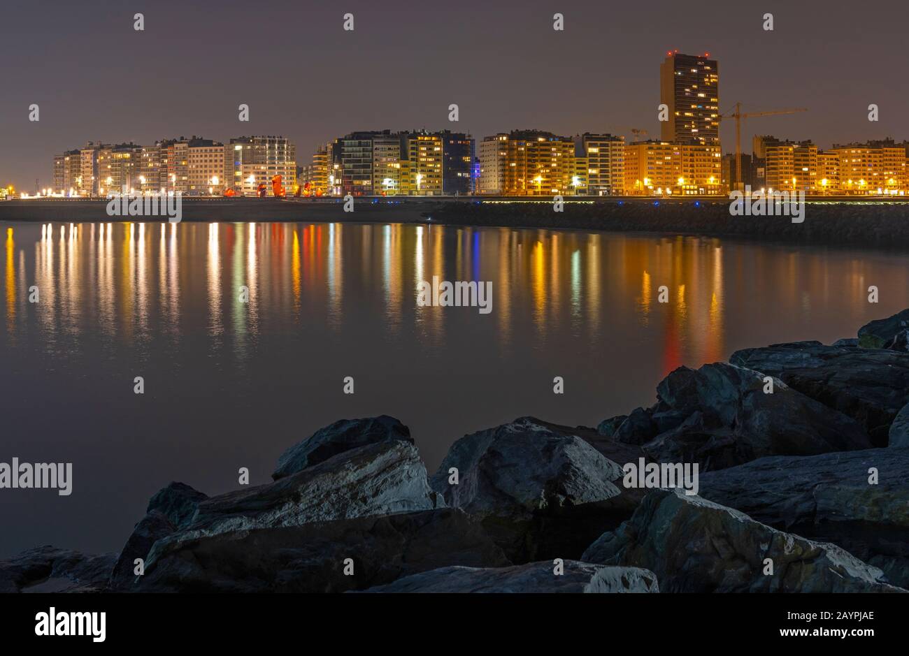 Die Skyline der Stadt Oostende (Ostende) mit Wasser und Pier in der Nacht mit ihren Lichtern im Nordseehafen, Belgien. Stockfoto