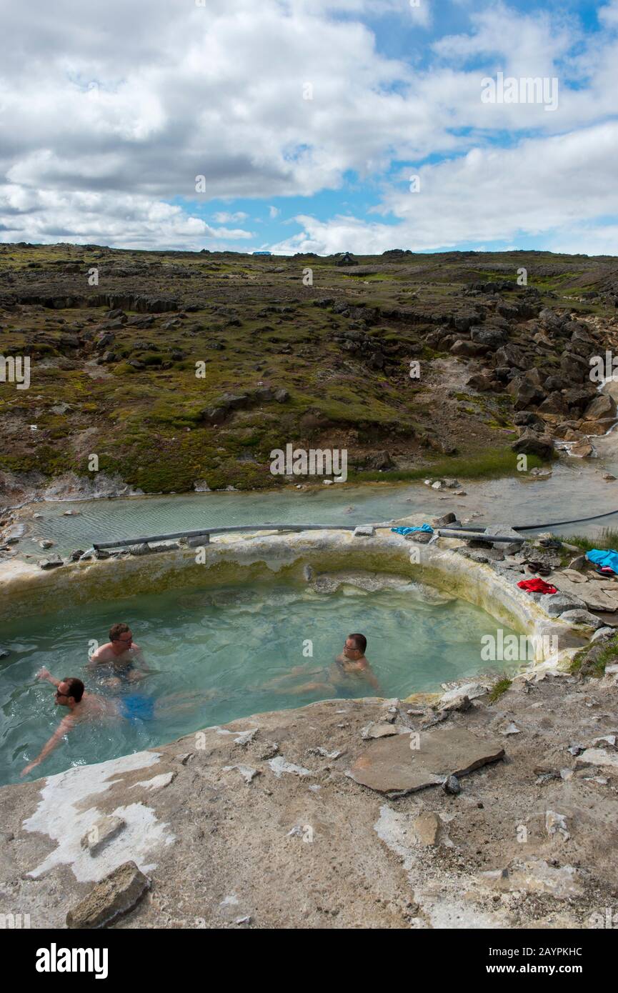 Die Menschen baden in einem Pool, der von heißen Quellen in Hveravellir gespeist wird, einem geothermischen Gebiet mit Fumarolen und mehrfarbigen heißen Pools im zentralen Hochland von Stockfoto