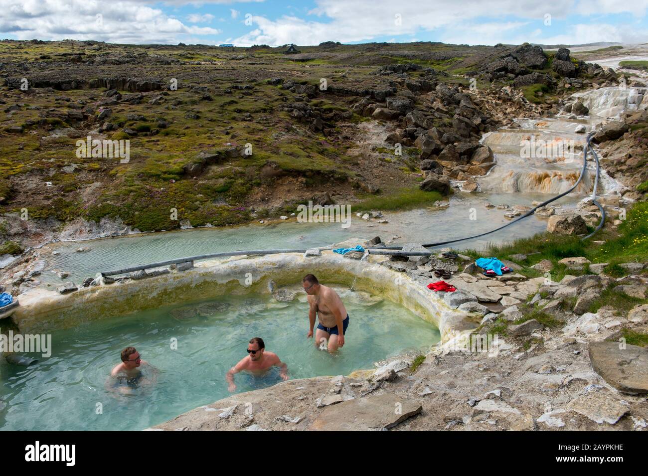 Die Menschen baden in einem Pool, der von heißen Quellen in Hveravellir gespeist wird, einem geothermischen Gebiet mit Fumarolen und mehrfarbigen heißen Pools im zentralen Hochland von Stockfoto