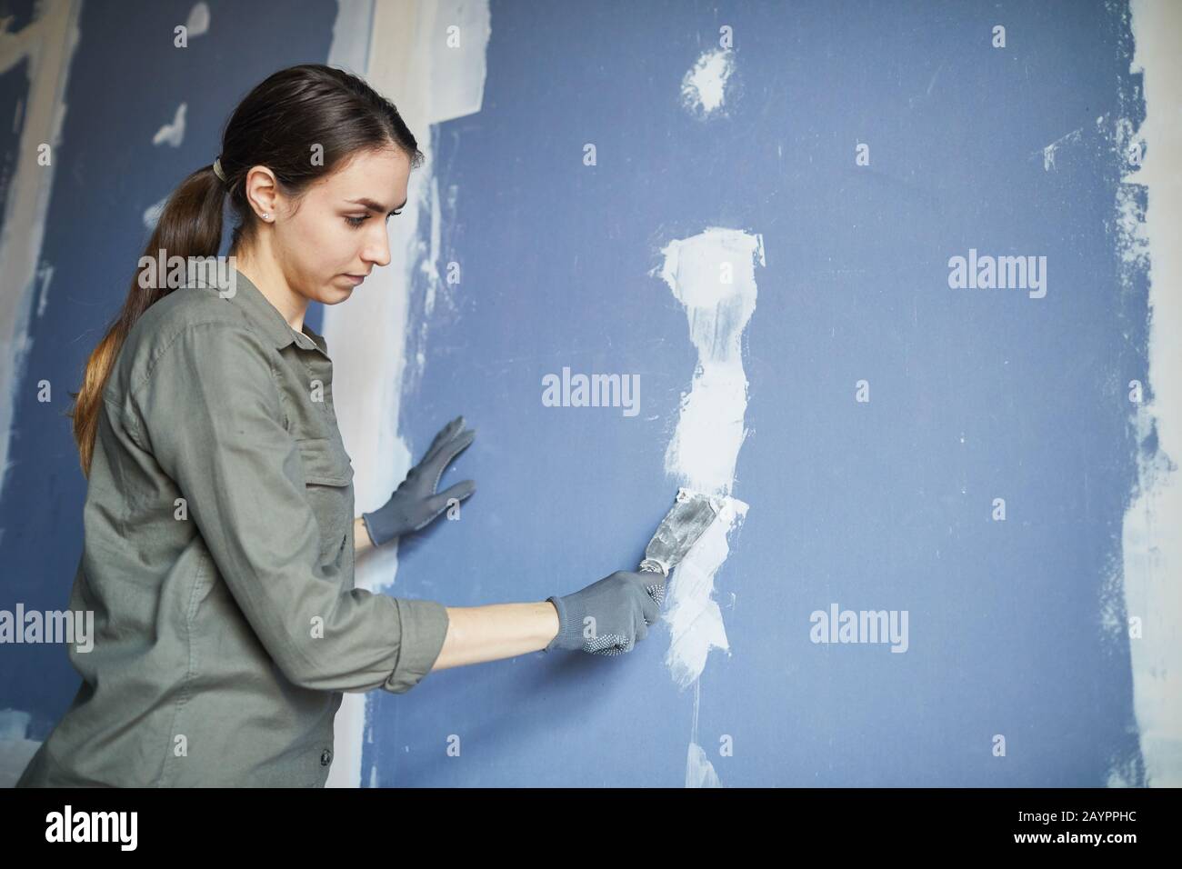 Taille oben Porträt der jungen Frau Glättung trockene Wand bei der Renovierung Haus für sich, Kopienraum Stockfoto