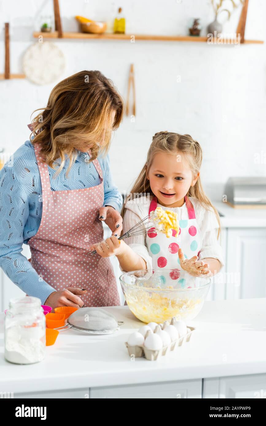 Mutter, die auf süße und schockierte Tochter mit Ballonwisk blickt Stockfoto