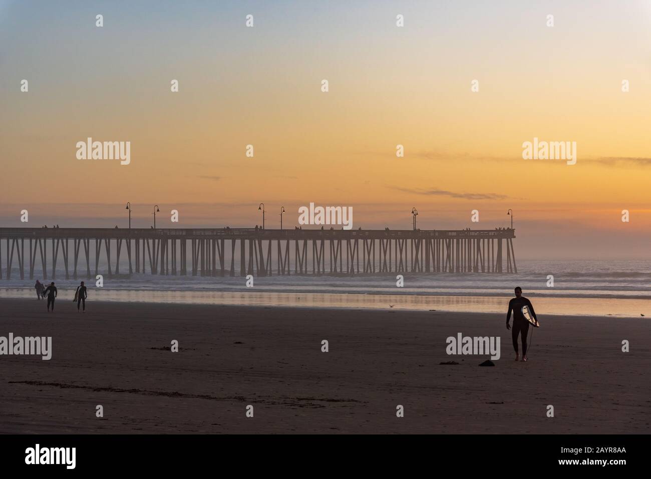 Surfer am Ufer des berühmten Pismo-Strandes in Kalifornien bei Sonnenuntergang. Stockfoto