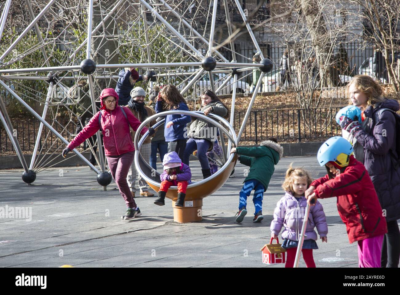 Kinder und Eltern genießen einen milden Wintertag auf einem Spielplatz im Prospect Park, Brooklyn, New York. Stockfoto