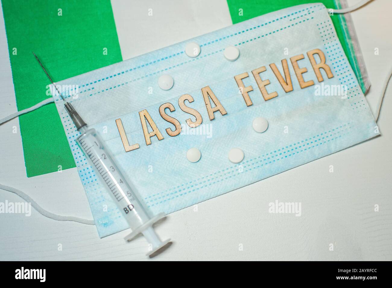 Nigerianische Flagge unter den Worten Lassa Fever Outbreak-Konzept. Atemschutzmaske und Spritze. Lassa hämorrhagisches Fieber LHF endemisch in Westafrika inkl Stockfoto