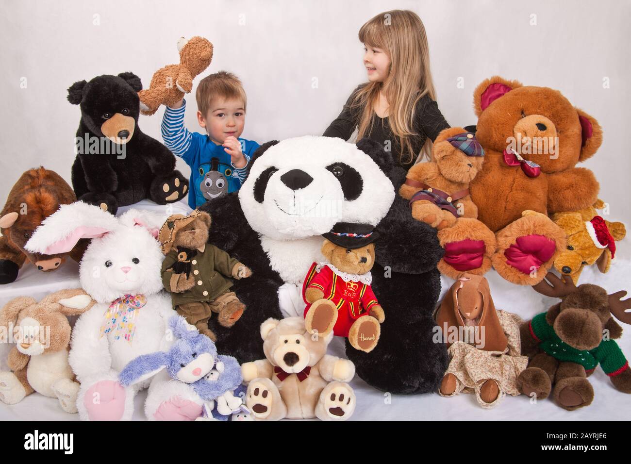 Sammlung von ausgestopften Tieren mit 2 jährigen Jungen hält seinen Teddy und seine 5-jährige Schwester Stockfoto