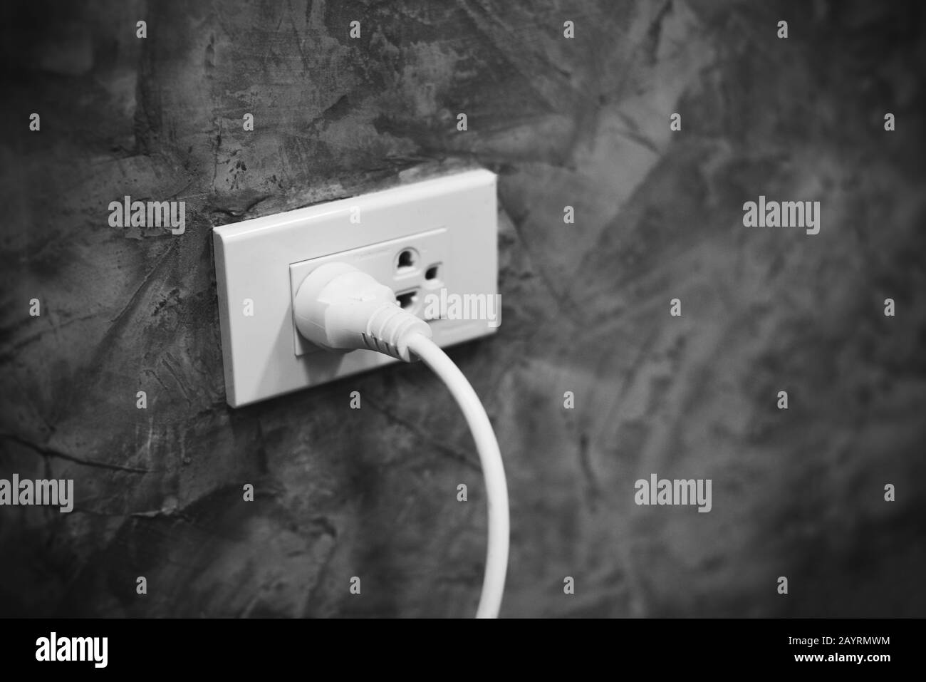 Der Stecker für die Haussteckdose wird mit einem weißen Netzkabel an die Wand gesteckt, der Stecker wird mit dem Netzstecker verbunden Stockfoto